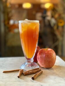 Cinnamon apple lemonade in a glass with fresh cinnamon sticks